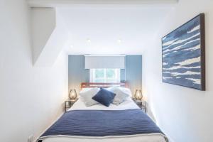 a bedroom with a bed with blue and white pillows at Lovely 2 bedroom house in Cambridge (sleeps 4) in Cambridge