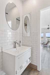 Baño blanco con lavabo y 2 espejos en Guest House Topsail, en Topsail Beach
