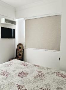 1 dormitorio con 1 cama y TV en la pared en Residencial Atalanta, en Bombinhas