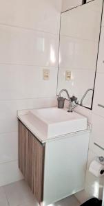 ein Bad mit einem Waschbecken und einem Spiegel in der Unterkunft Residencial Atalanta in Bombinhas