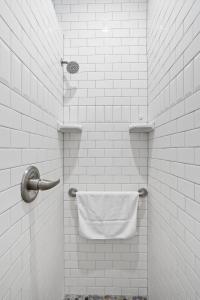- biały prysznic wyłożony kafelkami z ręcznikiem wiszącym na ścianie w obiekcie Guest House Topsail w mieście Topsail Beach