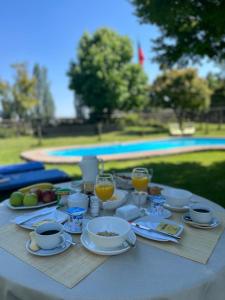 een tafel met glazen sinaasappelsap en borden met voedsel bij Casa Los Ciervos in Pirque