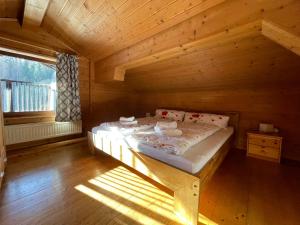 duże łóżko w drewnianym pokoju z oknem w obiekcie Gästehaus Katharina w mieście Hochfilzen