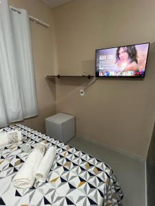 um quarto com uma televisão numa parede com uma cama em Suite 3- Nud Praia bonita Hospedagem em São Francisco do Sul
