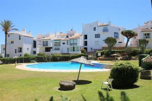 een zwembad met een parasol en een stoel en een aantal gebouwen bij Beachhouse GALORE in Estepona