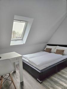 a bedroom with a bed and a desk and a window at Schneider Apartments in Neustadt am Rübenberge
