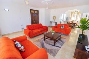 a living room with two orange couches and a table at 3 bedroom Nyali apartment in Mombasa