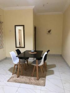a dining room with a black table and white chairs at Furnished 2bedroom Apt in Wuye in Wupa