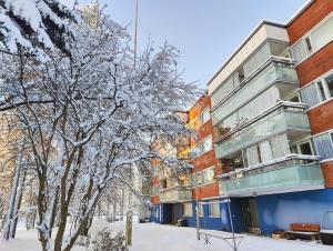 een met sneeuw bedekte boom naast een gebouw bij Spacious apartment with balcony and free WiFi in Rovaniemi
