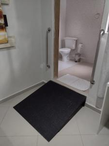 a bathroom with a toilet and a black rug at Pousada TOP in Mairiporã