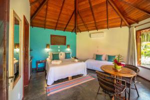 duas camas num quarto com mesa e cadeiras em Pousada Lagoa do Cassange em Maraú