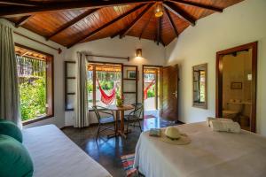 a bedroom with two beds and a table and chairs at Pousada Lagoa do Cassange in Marau