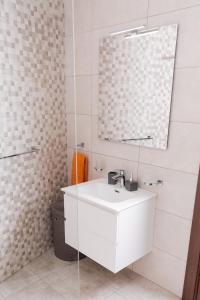 uma casa de banho com um lavatório branco e um espelho. em Azure FOUR em Żurrieq