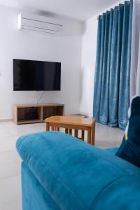 un soggiorno con divano blu e TV di Azure FOUR a Żurrieq