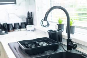 a black sink in a kitchen with a faucet at Modern 4-Bed Retreat with Garden in Manchester