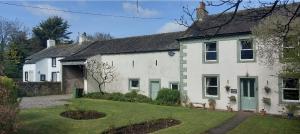 a white house with a green door and a yard at Molly The Vintage Caravan. in Wigton