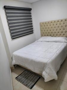 a bedroom with a bed and a window with a white bedspread at Casa del Arbol Apto. 301 in Medellín