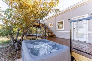a hot tub on a deck next to a house at Walnut Horizon Tiny Home With Observation Deck in Luckenbach