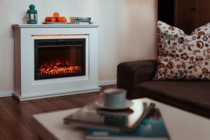 a fireplace in a living room with a couch and a table at Apartament 3 in Polanica-Zdrój