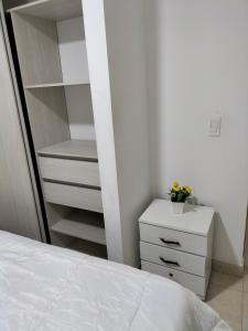 a bedroom with a white bed and a dresser at Casa del Arbol Apto. 301 in Medellín