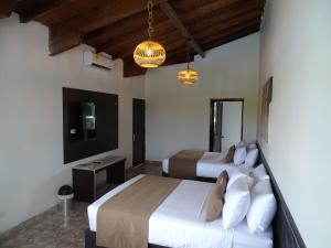 a bedroom with two beds and a television and chandeliers at Hotel Palmas De Alcalá in Playa Verde