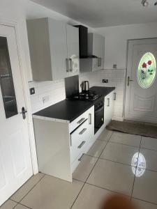a kitchen with white cabinets and a black counter top at High Street Lodge in Clowne