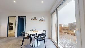 een eetkamer met een tafel en stoelen en een balkon bij Appartement Premium avec Terrasse - Parking privatif Gratuit - Fibre Wi-Fi - À 2 min Centre-Ville Dole in Dole