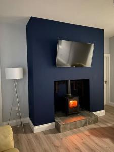 pared azul con chimenea y TV encima. en Modern 3 bed country cottage 