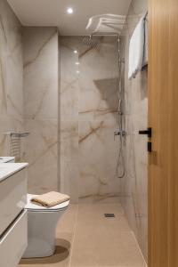 La salle de bains est pourvue d'une douche, de toilettes et d'un lavabo. dans l'établissement Bluetique Seaside Suites, à Gra Liyiá