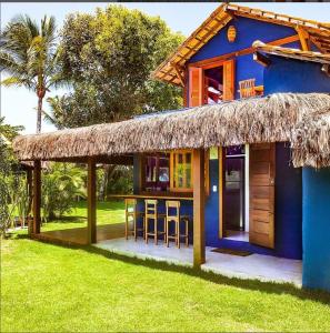una casa azul con un bar con techo de paja en Casa Bora Lá en Caraíva