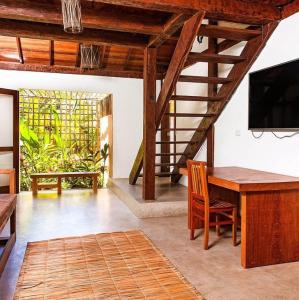 uma sala de estar com uma mesa de madeira e uma televisão em Casa Bora Lá em Caraíva