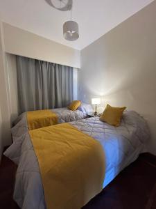 a bedroom with a large bed with yellow sheets at Departamento Caseros in Salta