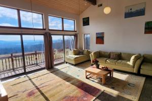 een woonkamer met een bank, een tafel en ramen bij Valley Views Serene Retreat 