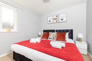 a bedroom with a large bed with red blanket at Modern Living in a 2BR near Milton Keynes in Milton Keynes
