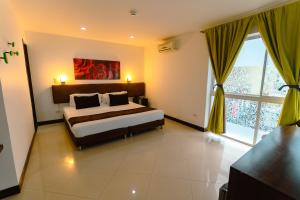um quarto com uma cama e uma janela grande em Hotel Boutique las Rosas 5 G em Medellín