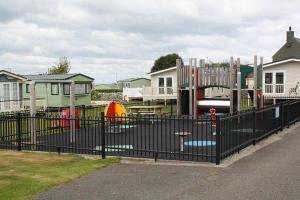 a playground behind a black fence in front of houses at Caravan 521 shuker in Talybont