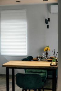 een eettafel met 2 groene stoelen en een raam bij Dream House in Vršac