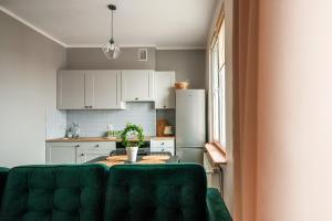 a kitchen with a table and a green couch at Ostróda Green Apartment in Ostróda