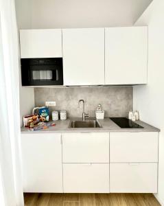 a white kitchen with a sink and a microwave at Andrea's 12 in Bari +28 photos