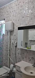 a bathroom with a sink and a toilet and a mirror at Pousada M&J in São Gabriel