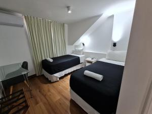 Habitación de hotel con 2 camas y escritorio en Hotel Santiago Patio Bellavista, en Santiago