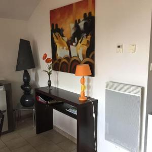 een bureau met een lamp en een schilderij aan de muur bij Gérardmer : appartement 43m2, classé 3*, vue lac in Gérardmer +1 foto