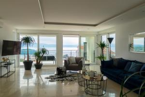 a living room with a blue couch and chairs and windows at The Grand View Villa in Njivice