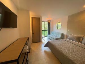 a bedroom with a bed and a couch and a table at Trip Monkey del Río in San Gil