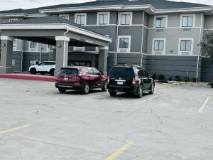two cars parked in a parking lot in front of a building at Fort Stockton Inn and Suites in Fort Stockton