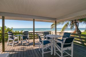 una terraza con sillas y mesas y vistas a la playa en The Tiki House, en Holmes Beach