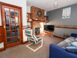 uma sala de estar com uma cadeira e uma lareira em Saddlers Cottage em Weymouth