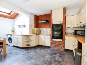 uma cozinha com armários brancos e uma parede de tijolos em Saddlers Cottage em Weymouth