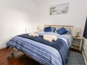 uma cama com lençóis azuis e brancos e almofadas azuis em Saddlers Cottage em Weymouth