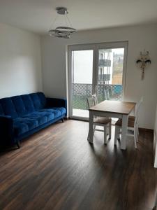 a living room with a blue couch and a table and chairs at Apartament 4You in Żywiec